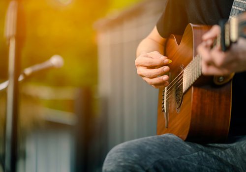 Closeup of someone playing an acoustic guitar outside