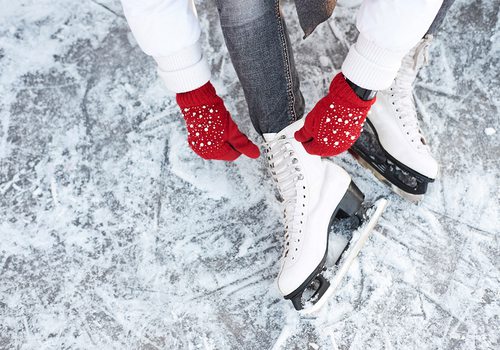 Lacing up ice skates with red gloves